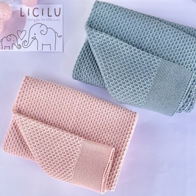 Dois cobertores de malha rosa e azul com padrão de losangos e cartão com elefantes e texto LICILU