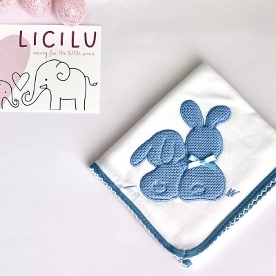 Pano de bebé branco com bordado de coelhinhos azuis e cartão com elefantes e texto LICILU
