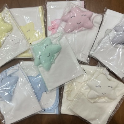 Peças de roupa branca embalada com apliques de peluche em forma de nuvens e estrelas sorridentes coloridas