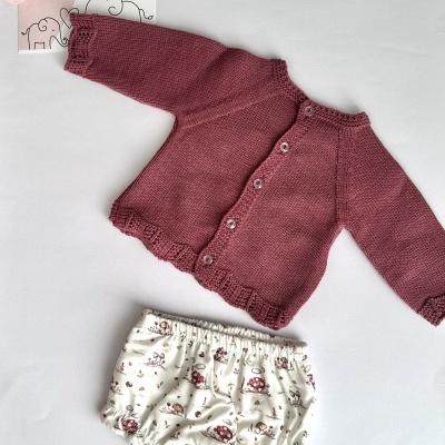 Conjunto infantil com camisola rosa de malha e calções brancos com padrão de cogumelos.