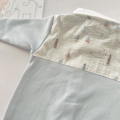 Body de bebé azul claro com parte branca estampada de barcos e faróis.