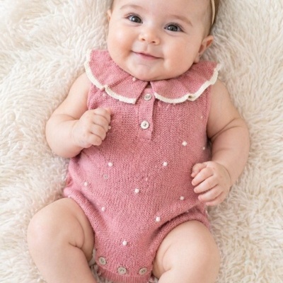 Bebé deitado com roupa cor-de-rosa em malha e colarinho branco