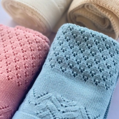 Quatro mantas de malha coloridas e enroladas com padrões rendados