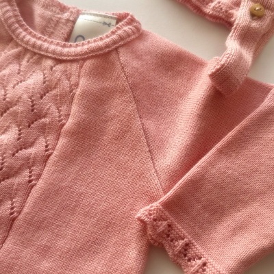 Conjunto de roupa de bebé em malha rosa com padrão trançado e botão de madeira
