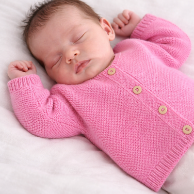 Bebé dormindo com casaco rosa de malha e botões de madeira