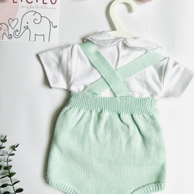Roupa de bebé com body branco e jardineira verde água em fundo branco.