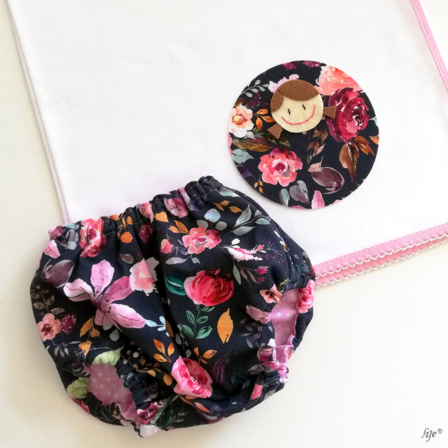 Fralda floral colorida com toalha branca com aplicação decorativa circular e barra rosa