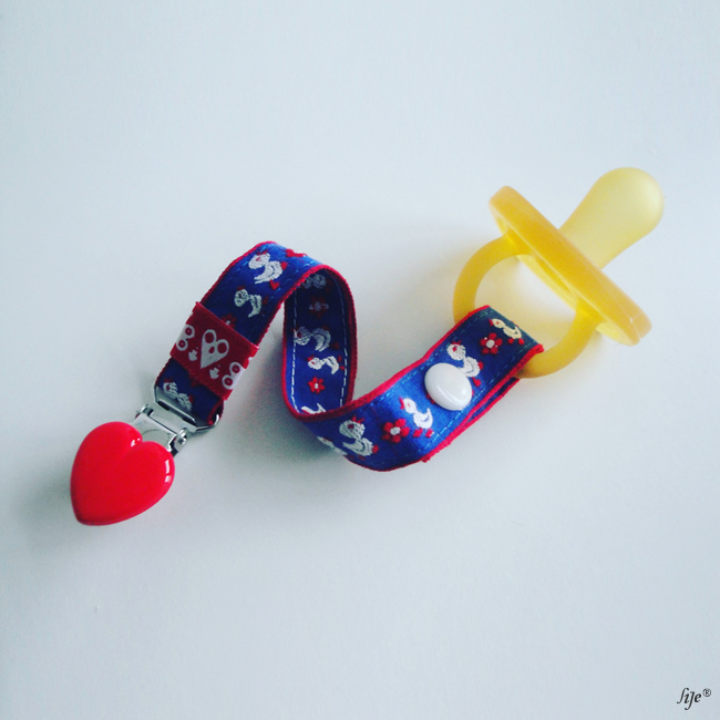 Chupeta amarela com suporte azul decorado e prendedor vermelho em forma de coração