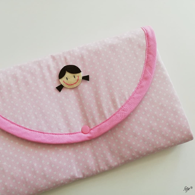 Estojo rosa claro com pontos brancos e aplicação de rosto de menina em feltro