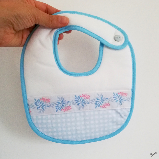 Babete de bebé branco com borda azul clara e padrão floral azul e rosa