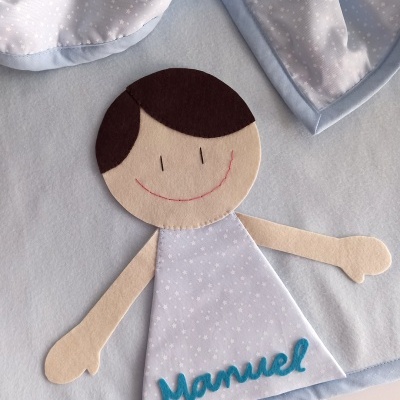 Tecido para bebé com figura de menino em feltro e vestido azul com estrelas e nome Manuel.