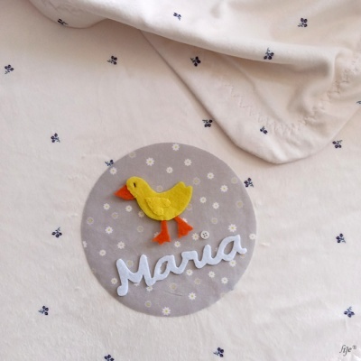 tecido bege claro com pato amarelo de feltro e nome Maria bordado