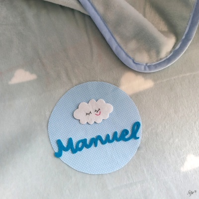 Manta cinza claro com borda azul e aplicação com nome Manuel e nuvem em tecido azul claro
