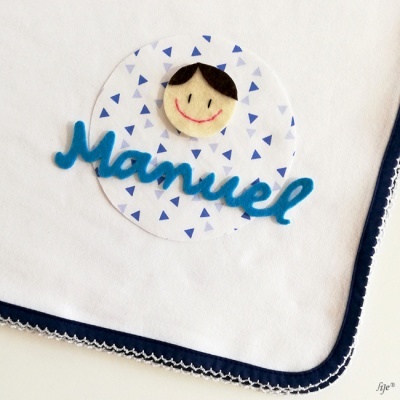 Fralda branca personalizada com nome Manuel e rosto sorridente em feltro