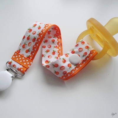 Chupeta amarela com presa de tecido com padrão de laranjas e clip metálico