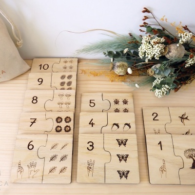 Blocos de madeira numerados e ilustrados com tema da natureza ao lado de ramo de flores secas e bolsa de tecido