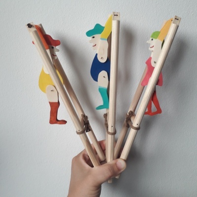 Três marionetas de madeira coloridas seguradas por uma mão