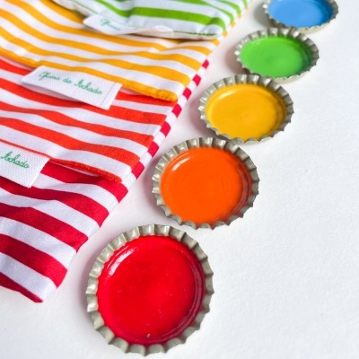 Camisolas listradas coloridas ao lado de tampas de garrafa coloridas