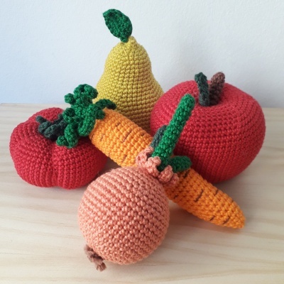 Legumes e frutas de croché coloridos sobre mesa de madeira