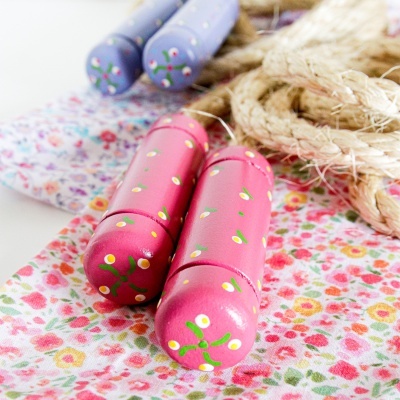 Paus de madeira rosas decorados com flores sobre tecido floral e cordas de sisal