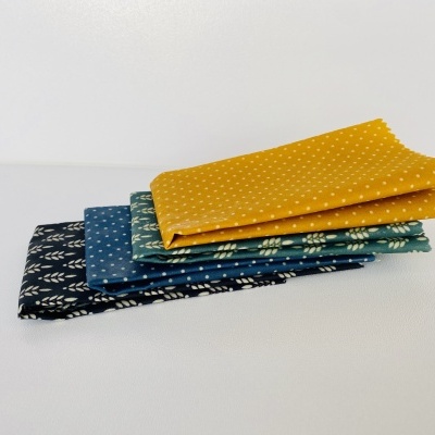 Quatro tecidos dobrados em azul, verde e amarelo com padrões em branco