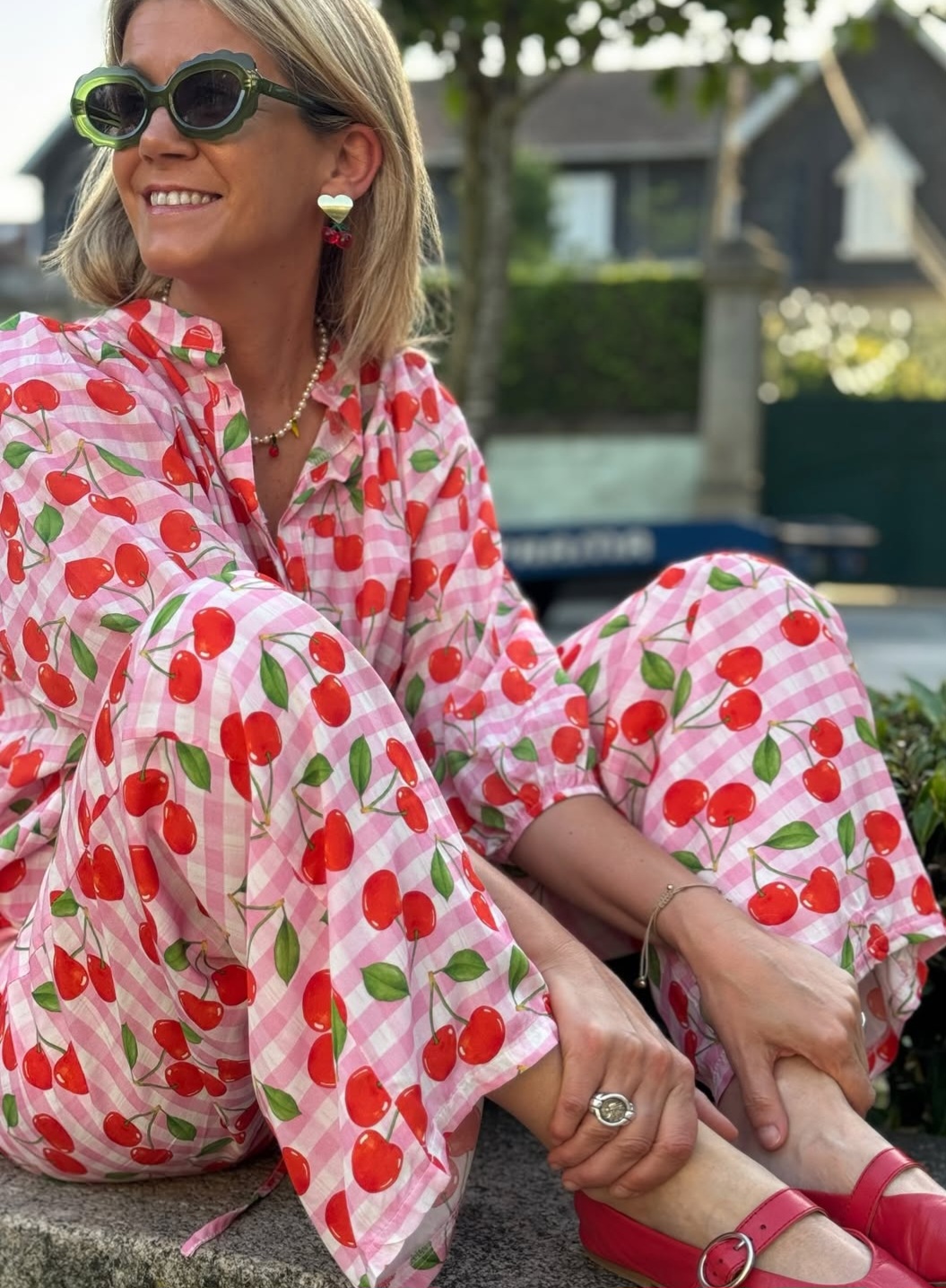 Mulher sentada com pijama rosa de cerejas e sapatos rosa