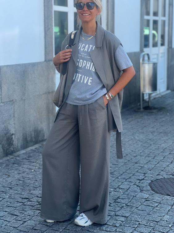 Conjunto Safari Mulher com conjunto cinza, t-shirt com texto branco, calças largas e sapatilhas brancas