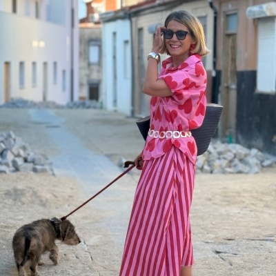 Mulher com vestido rosa estampado a passear cão