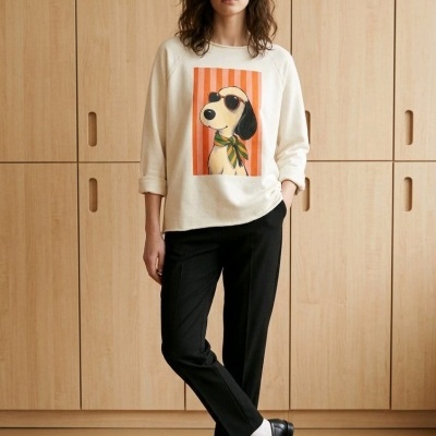 Mulher com sweatshirt creme com estampa de cão, calças pretas e sapatos pretos com meias brancas