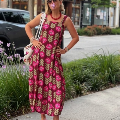 Mulher de vestido longo floral rosa e castanho com acessórios coloridos na rua urban