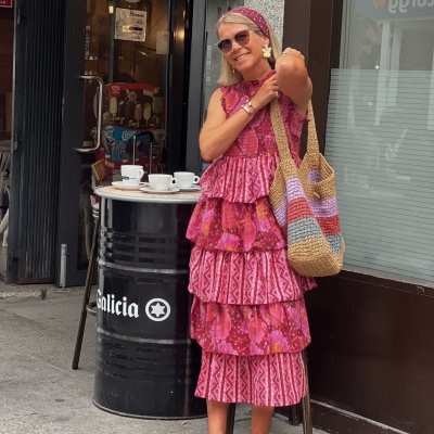 Mulher com vestido rosa e carteira de crochê junto a barril preto com texto Galicia