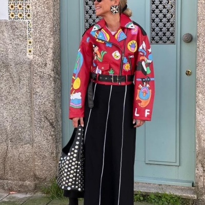 Mulher vestindo casaco vermelho estampado e saia preta longa com costuras brancas