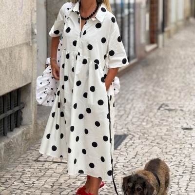 Vestido branco com bolinhas pretas e sandálias vermelhas numa rua com cão