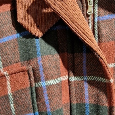 Casaco xadrez vermelho e verde com gola castanha canelada e fecho de correr