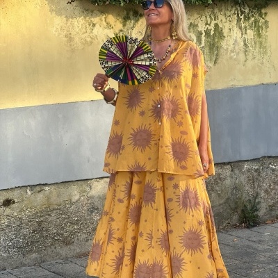 Vestido amarelo com padrão de sóis cor de vinho e senhora com leque colorido