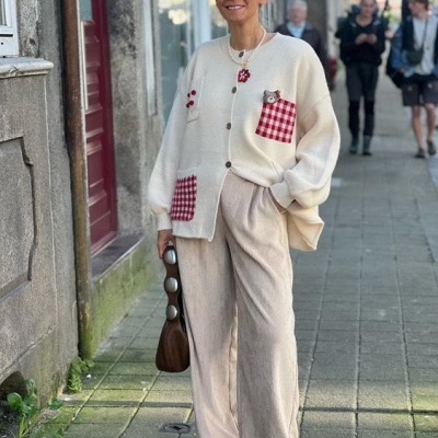 Mulher com casaco branco com bolsos quadriculados vermelhos e brancos e calças largas bege na rua