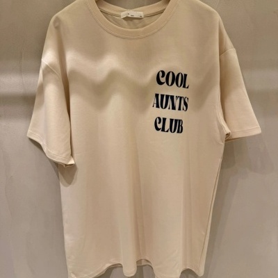 T-shirt bege clara com texto Preto COOl AUNTS CLUB pendurada num cabide