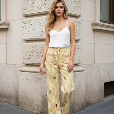 Mulher vestindo calças xadrez amarelo claro com bolsos de coração, top branco e ténis brancos, em rua urbana