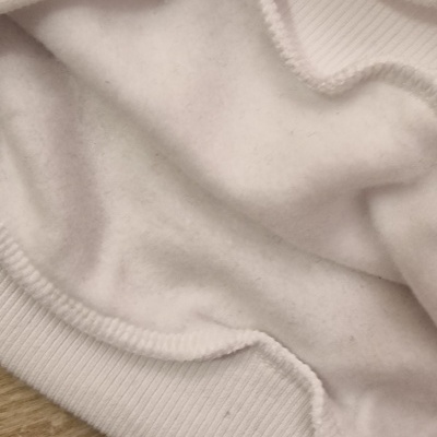 Tecido branco felpudo com bainha, sobre madeira clara