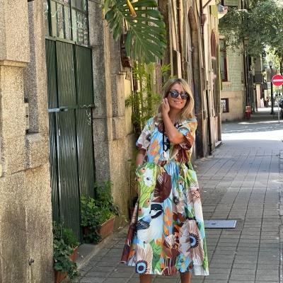 Mulher de vestido midi floral colorido numa calçada urbana