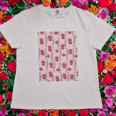 T-shirt branca com estampa de tomates e peixes em fundo rosa, etiqueta da LInestore, sobre flores coloridas