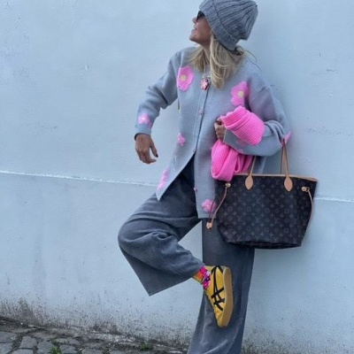 Mulher com roupa cinzenta e cor-de-rosa numa parede branca