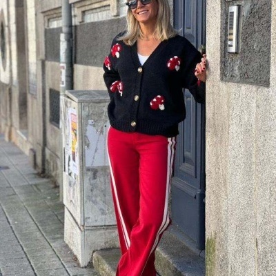 Mulher com casaco de cogumelos preto e calças vermelhas ao ar livre