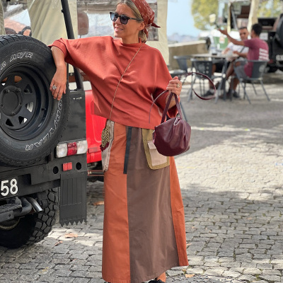 Mulher elegante com roupa tricolor com bolsos e sapatos pretos ao lado de jipe preto com pneu Goodyear