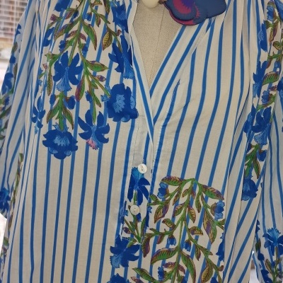 Vestido branco com riscas azuis e flores azuis, colar branco e azul.