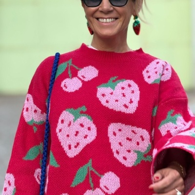 Suéter vermelho com morangos e cerejas, óculos de sol pretos, brincos vermelhos