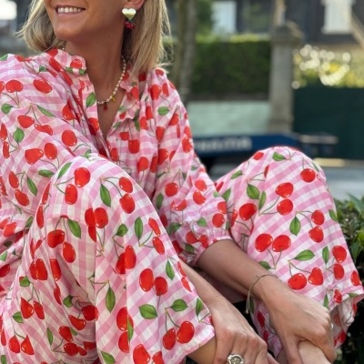 Mulher sentada com pijama rosa de cerejas e sapatos rosa