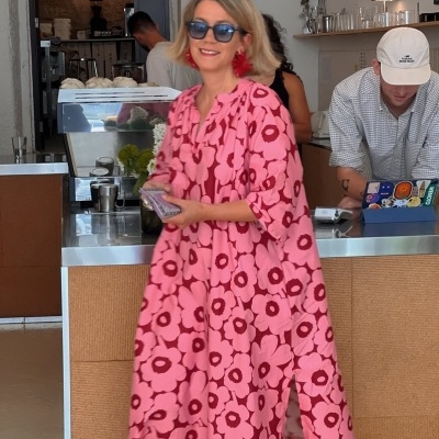 Vestido rosa com flores vermelhas usado por mulher numa cafetaria