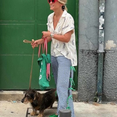 Mulher com calças xadrez e óculos de sol vermelhos com cão na rua