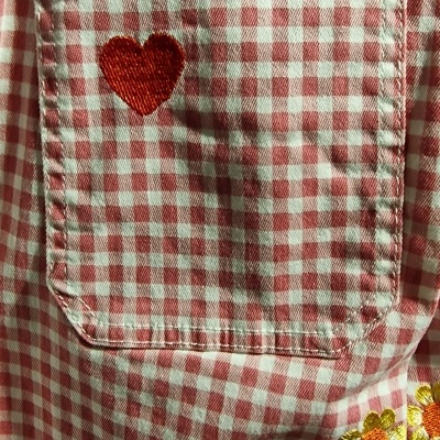 Roupa xadrez vermelho e branco com bordados de coração e flores.